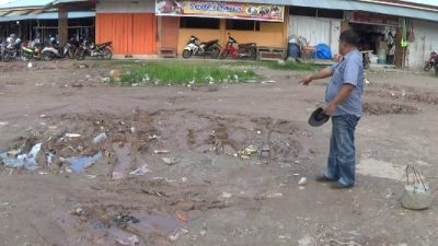 Seorang pedagang menunjukkan jalan dan halaman pasar sentral kolaka yang berlumpur dan becek. FOTO : LAN