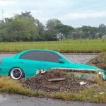 Mobil Sedan hijau yang terpeorosok di persawahan warga. FOTO : BISMA SURYA KURNIAWAN