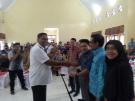Ketua KIP Aceh Singkil Yarwin Adi Dharma menyerahkan berkas berita acara, kepada bupati Aceh Singkil terpilih Dulmusrid Kamis(6/4) di gedung serbaguna pulosarok. FOTO : MAN