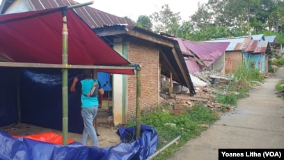 Seorang warga sedang mendirikan tenda terpal di depan rumahnya yang rusak akibat gempa di dusun Petakeang, Kecamatan Tapalang, Sulawesi Barat. Jumat (5/1/2021). (Foto: VOA/Yoanes Litha)