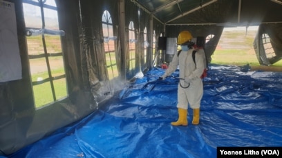 Petugas kesehatan menyemprotkan cairan disinfektan di tenda jelang pelaksanaan kegiatan psikososial di shelter Terintegrasi di Stadion Manakarra, Mamuju, Sulawesi Barat, Minggu, 31 Januari 2021. (Foto: Yoanes Litha/VOA)