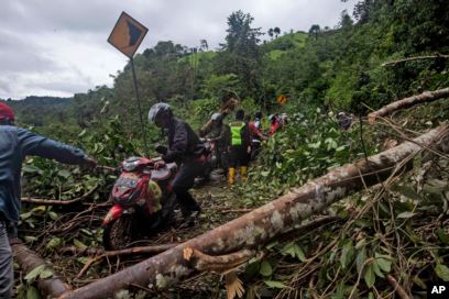 Sejumlah pengendara motor melewati jalan yang rusak akibat tanah longsor yang dipicu gempa dekat Mamuju, Sulawesi Barat, Sabtu, 16 Januari 2021.(Foto: AP)