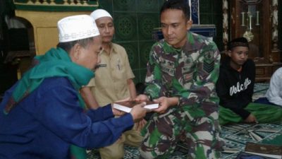 Anggota koramil Sukapura Sersan mayor Dodik mentyerahkan Al-quran kepada salah satu pengasuh TPQ. FOTO : ASL