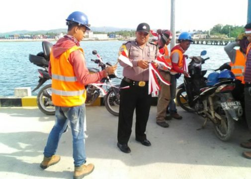 Anggota Kepolisian KP3 membagikan souvenir bendera kepada setiap warga di kawasan pelabuhan nusantara. FOTO : ONNO