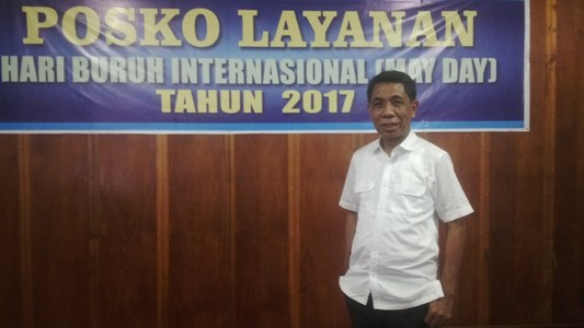 Kadis tenaga Kerja dan Transmigrasi Sultra H. Saemu Alwi berfose di latar spanduk Poskoh pelayanan Hari Buruh Internasional. FOTO : BAIM