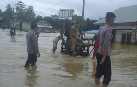 Banjir yang melanda di wilayah Konawe Selatan, khususnya di Laeya . Tampak seorang PNS menggunakan jasa ojek untuk melakukan penyebrangan. FOTO : MAHIDIN