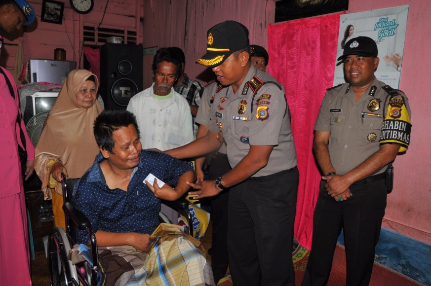 Kapolres Kota langsa AKBP Satya Yudha Prakasa,SIK saat menyerahkan bantuan kursi roda kepada Husaini yang merupakan warga yang menerita kelumpuan. FOTO : ROBY SINAGA