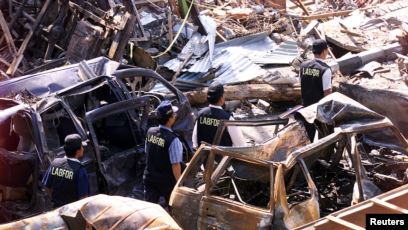 Polisi forensik berjalan melewati mobil-mobil yang hancur di dekat lokasi ledakan bom 12 Oktober 2002 di Kuta, Bali, 18 Oktober 2002. Tiga tersangka yang diduga terlibat pemboman di Indonesia antara tahun 2002-2003 akan diadili pengadilan militer AS. (Foto: Reuters)