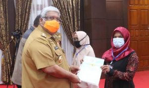 Gubernur Sulawesi Tenggara (Sultra) Ali Mazi, saat meneyerahkan menyerahkan sertifikat tanah bidang kepada masyarakat yang tersebar di 17 kabupaten/kota se-Sultra. Foto: Ewit/Kominfo