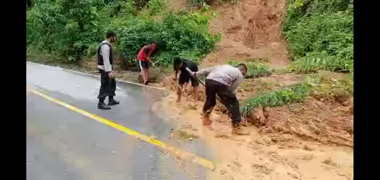 Masyarakat gotong royong membersikan tanah longsor yang menutupi jalan akibat hujan deras