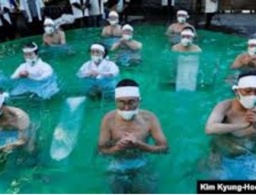 Peserta yang mengenakan masker pelindung wajah di tengah wabah Covid-19, berdoa saat mereka mandi es selama upacara untuk memurnikan jiwa mereka dan berharap untuk mengatasi pandemi di kuil Teppozu Inari di Tokyo, Jepang, 10 Januari 2021. (Foto: REUTERS/K