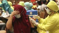 Seorang warga memalingkan wajahnya saat menerima vaksin COVID-19 dalam vaksinasi massal untuk para pedagang di Tangerang, 1 Maret 2021.
