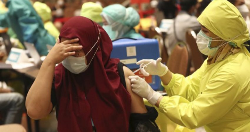 Seorang warga memalingkan wajahnya saat menerima vaksin COVID-19 dalam vaksinasi massal untuk para pedagang di Tangerang, 1 Maret 2021.