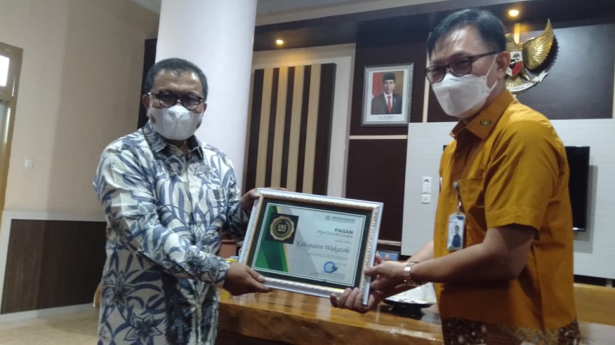 Bupati Wakatobi Arhawi saat menerima Piagam BPJS dari Deputi Direksi Wilayah Sulselbartramal) Dr. Beno Herman, di Wakatobi, Jum'at (25/06/2021).