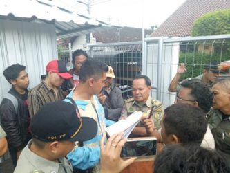 Pemilik lahan bersama satpol PP melakukan diskusi dengan warga setelah melakukan penyegelan. FOTO : NADHIR