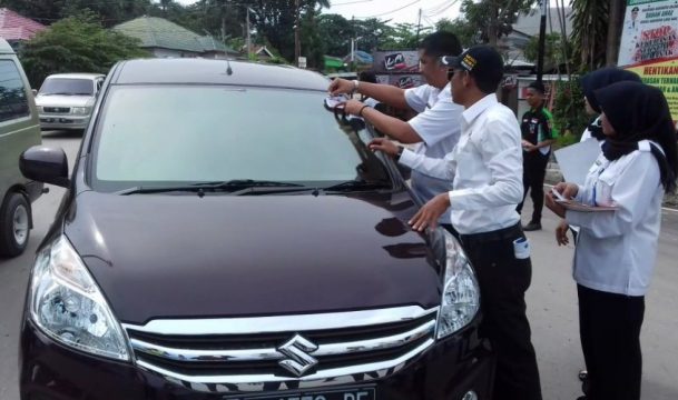 Kepala BNNK Kolaka saat membagikan stiker anti narkoba kepada setiap jkendaraan yang melintas di depan kantor BNNK Kolaka. FOTO : ASDAR LANTORO
