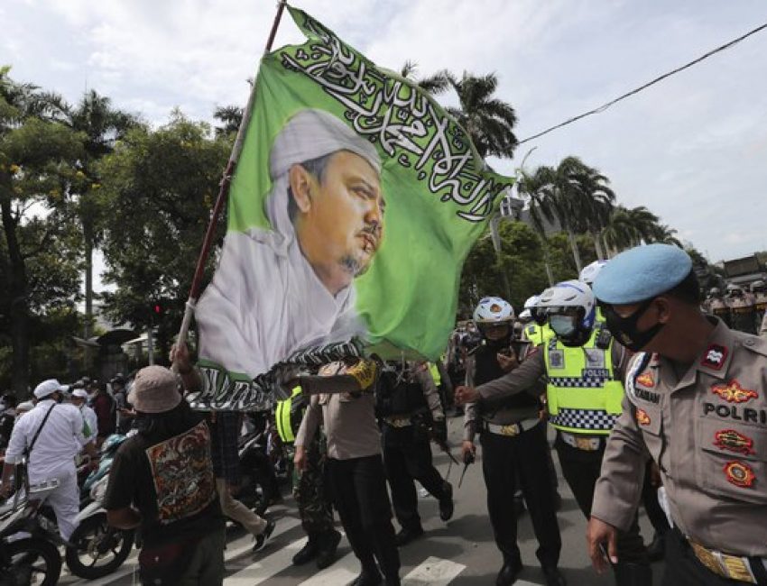 Para pendukung Muhammad Rizieq Shihab, Pimpinan Front Pembela Islam (FPI), sambil membawa bendera besar bergambar ulama kontroversial itu melakukan unjuk rasa di Jakarta 18 Desember 2020.