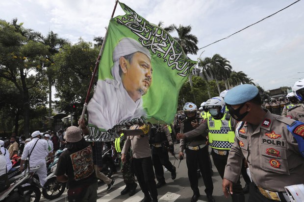Para pendukung Muhammad Rizieq Shihab, Pimpinan Front Pembela Islam (FPI), sambil membawa bendera besar bergambar ulama kontroversial itu melakukan unjuk rasa di Jakarta 18 Desember 2020.
